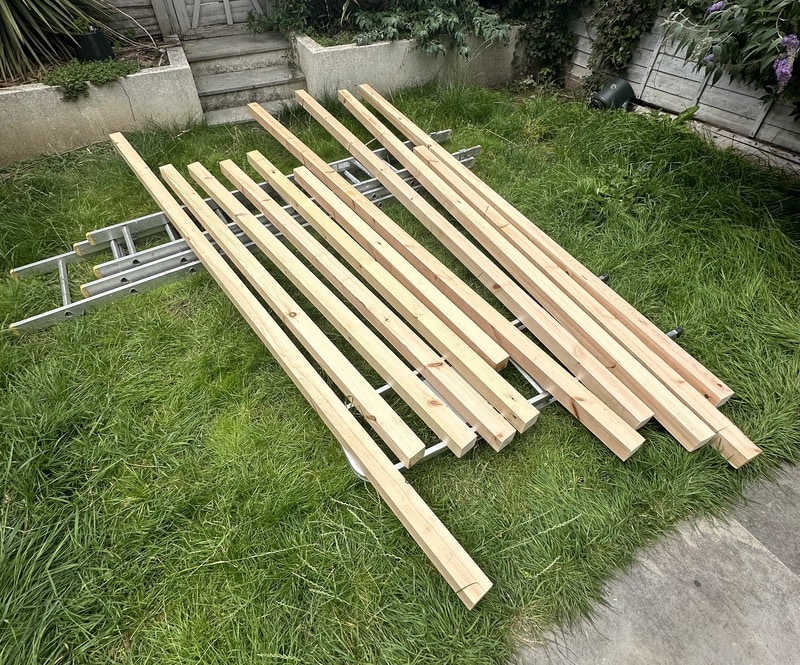 11 wooden beams are resting on ladders that we placed (lying down) on the lawn. They are ready to be varnished.