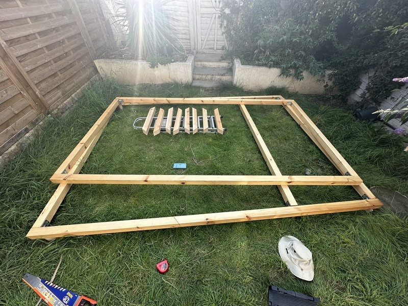 Two rectangles are stacked on the grass. Shorter stabilising blocks are in the middle, waiting to be varnished before we can attach them.