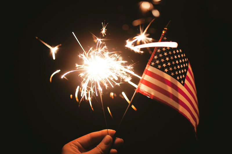 a hand holding a flag and sparkler
