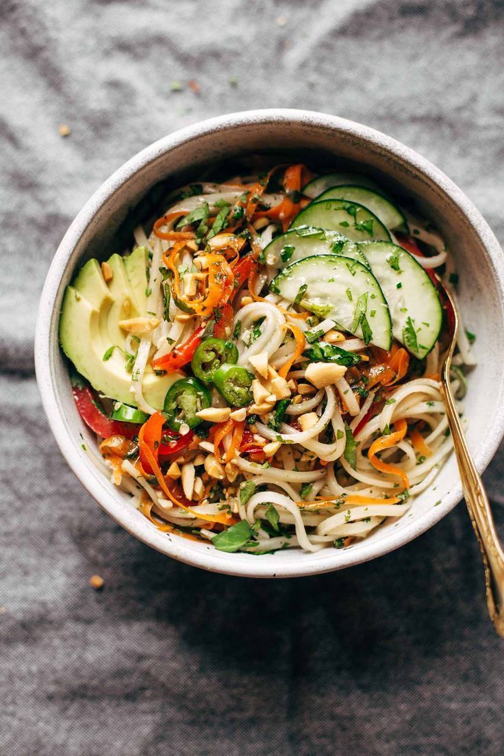 a bowl of noodles with vegetables and a spoon