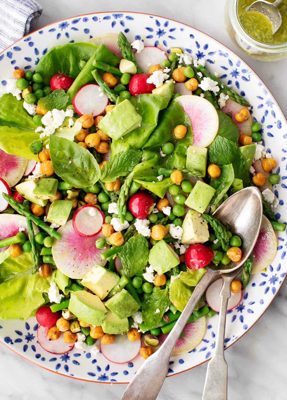 a plate of salad with vegetables and a spoon
