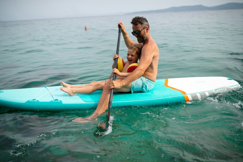 a man and child on a paddle board in the water