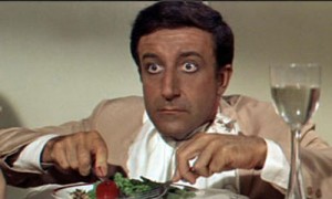 Peter Sellers sem Hrundi V. Bakshi á alltof litlum stól í The Party.