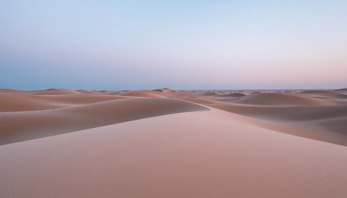 Twilight Over Serene Sand Dunes in the Desert This serene image captures the tranquil beauty of sand dunes bathed in twilight light. The soft glow creates an atmospheric setting as the undulating lines of the dunes lead the viewer's eye toward the horizon. The macro lens helps retain details in the shifting sands, while the natural muted color palette showcases the gentle blues and warm browns of the landscape. This photograph evokes a feeling of peace and quietude, perfect for showcasing the beauty of desert environments.