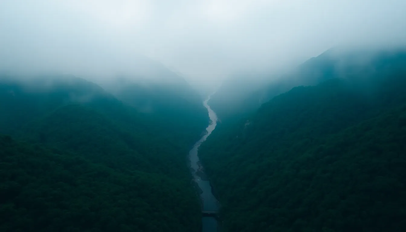Experience the serenity of a mountainous landscape captured from above during a foggy morning. This aerial view highlights the lush greenery of valleys intertwined with a winding river, creating inviting leading lines. The soft light filtered through the mist adds an ethereal quality, evoking feelings of peace and tranquility. Perfect for showcasing nature's beauty, this image invites the viewer to explore its remote charms.