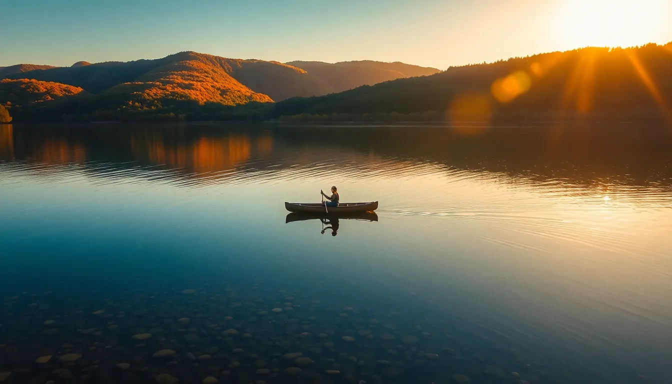 This aerial image captures a peaceful expression of nature as a lone canoeist glides across a tranquil lake during golden hour. The vibrant autumn colors reflect beautifully on the water surface, creating a harmonious blend of warm orange and deep reds. Surrounded by hills, the scene is beautifully composed to highlight the solitude of the canoeist. A gentle breeze creates ripples, enhancing the serene atmosphere.