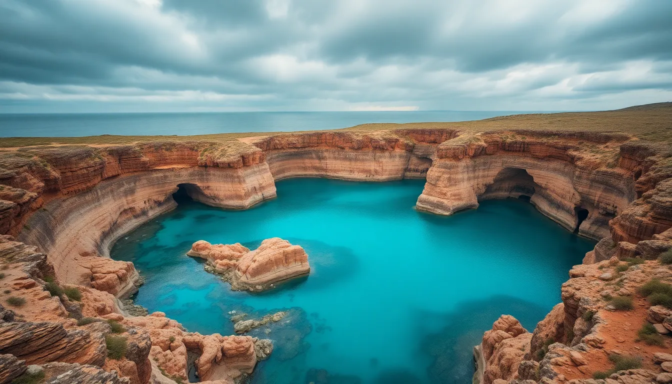 This aerial photograph reveals a breathtaking turquoise lagoon bordered by rugged cliffs, under an overcast sky that adds drama to the scene. The turquoise water contrasts beautifully with the earthy tones of the cliffs, emphasizing nature's artistry. The composition centers on the lagoon, showcasing its unique shape and the intricate textures of both the water and the rocky landscape. This image captures the raw beauty and tranquility of coastal environments.