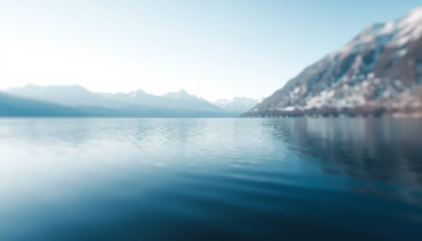 This breathtaking aerial image captures a serene lake nestled among majestic snow-capped mountains during the early morning light. The cool blue tones of the water create a perfect mirror for the clear sky, while gentle ripples add a sense of calmness. A shallow depth of field focuses on the lake’s shores, while the distant mountains fade into a dreamy blur, enhancing the tranquil atmosphere. This image invites viewers to escape into the serene beauty of nature.