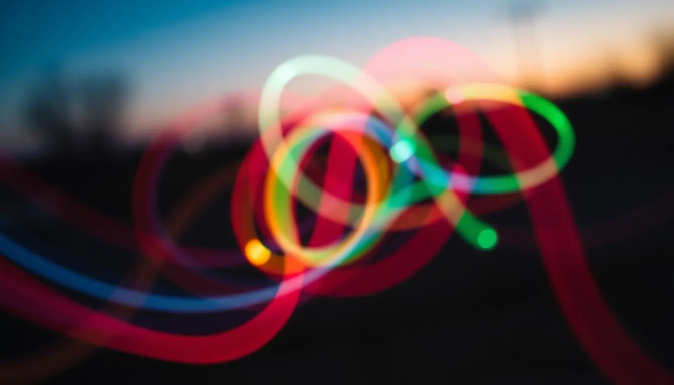A vibrant and dynamic portrayal of light trails created by a spinning light toy at dusk. The image captures the energy and movement of the lights, weaving through the frame in a colorful display. The selective focus emphasizes the bright trails while the soft background creates an ethereal atmosphere. The rich saturation and interplay of cool and warm tones enhance the excitement of the scene, making it a captivating abstract representation of light in motion.